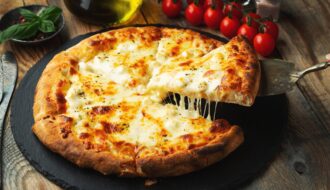 A slice of hot Italian pizza with stretching cheese. Pizza four cheeses with basil.