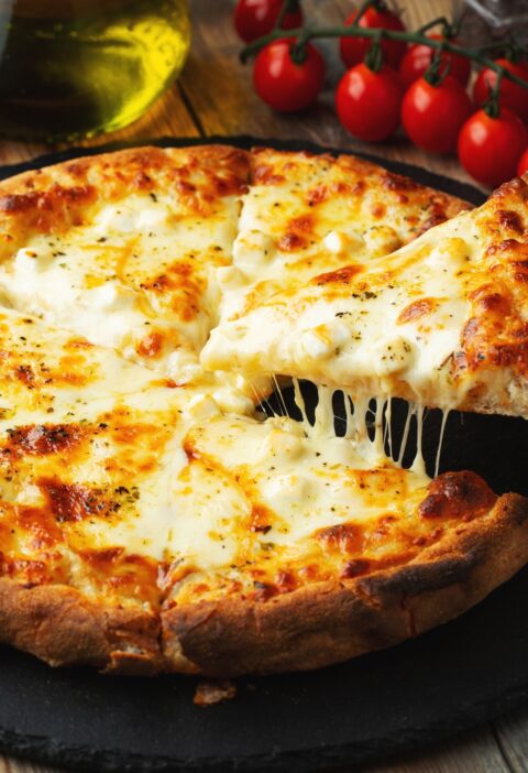 A slice of hot Italian pizza with stretching cheese. Pizza four cheeses with basil.