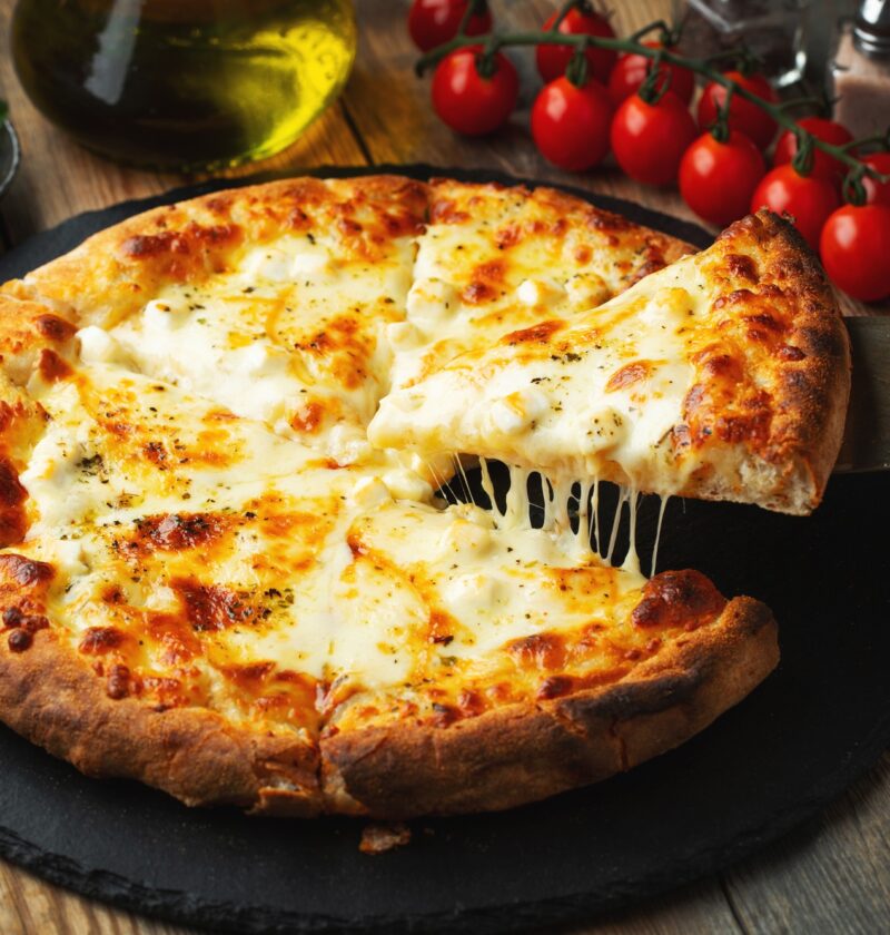 A slice of hot Italian pizza with stretching cheese. Pizza four cheeses with basil.