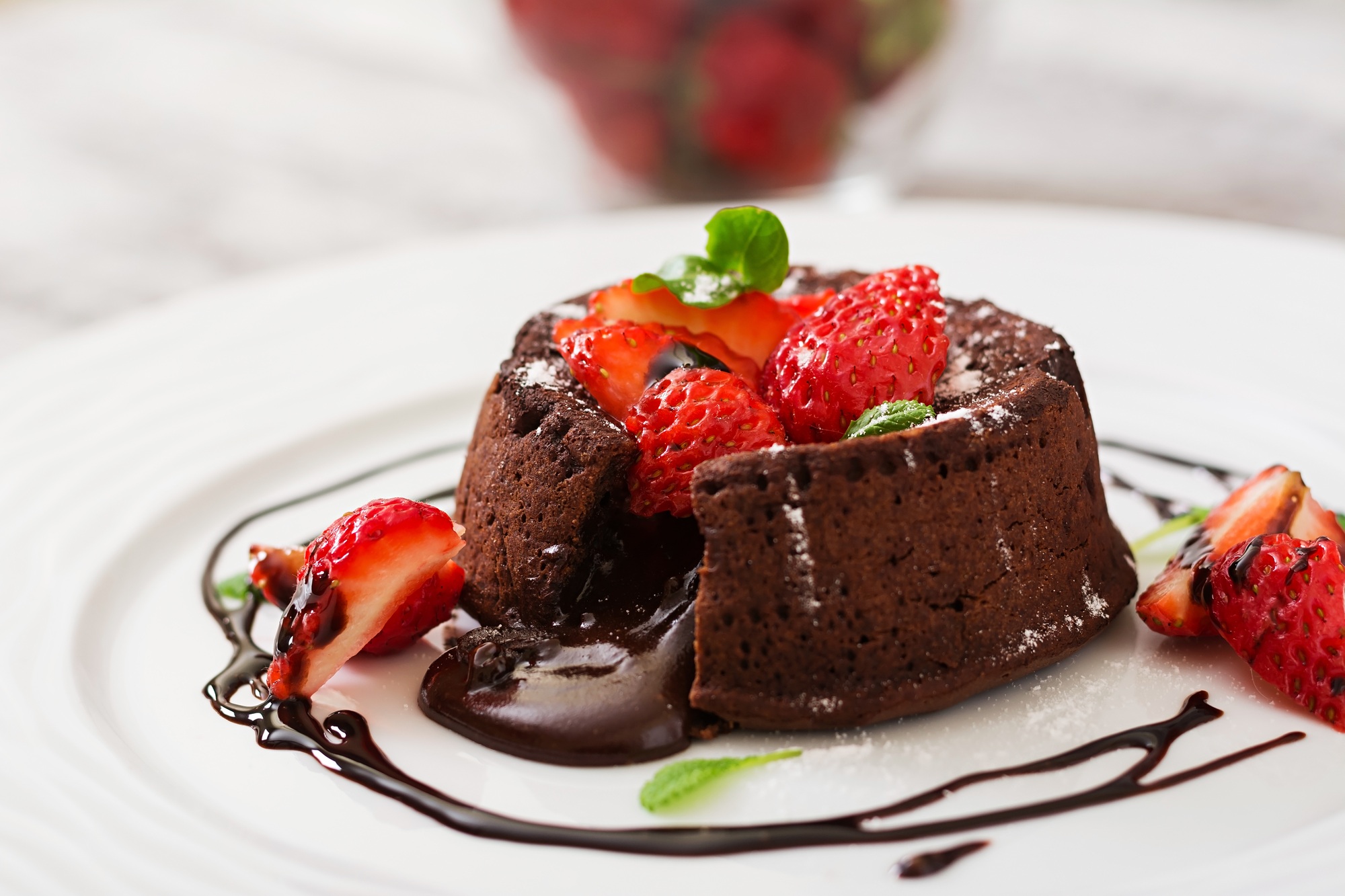 Chocolate fondant (cupcake) with strawberries and powdered sugar
