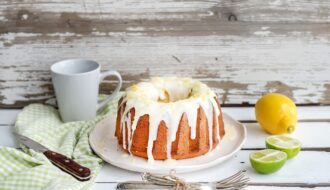 Moist lime and lemon bundt yoghurt cake, white rustic wooden background.
