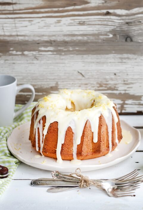 Moist lime and lemon bundt yoghurt cake, white rustic wooden background.