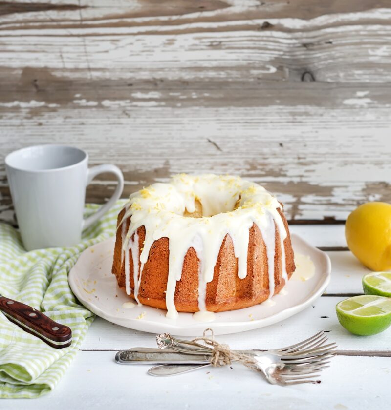 Moist lime and lemon bundt yoghurt cake, white rustic wooden background.