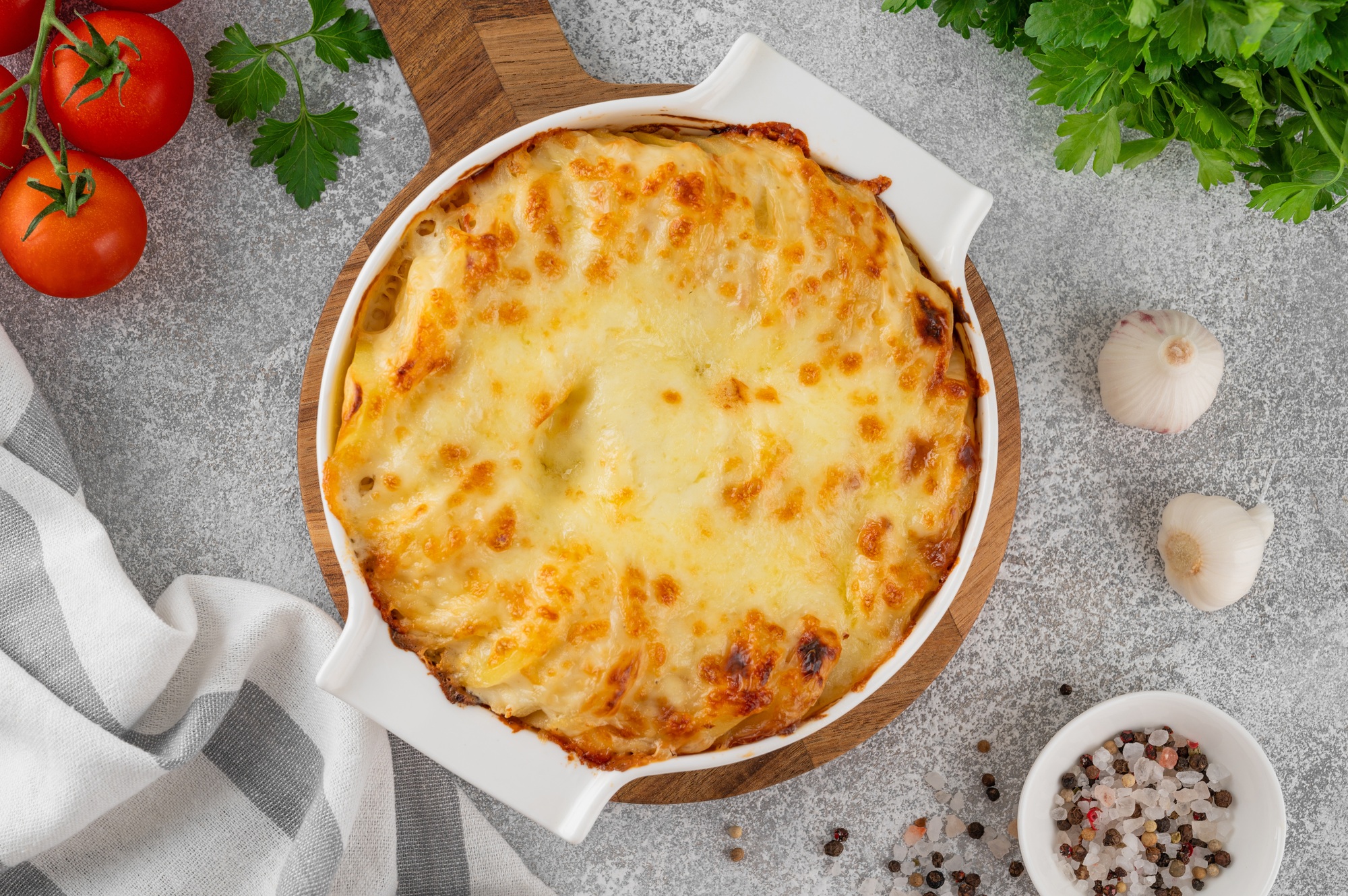 Potato gratin with cream, cheese and garlic in a white ceramic form. Potato casserole. Top view