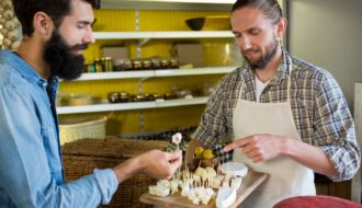 Staff showing a sample of cheese to customer at counter