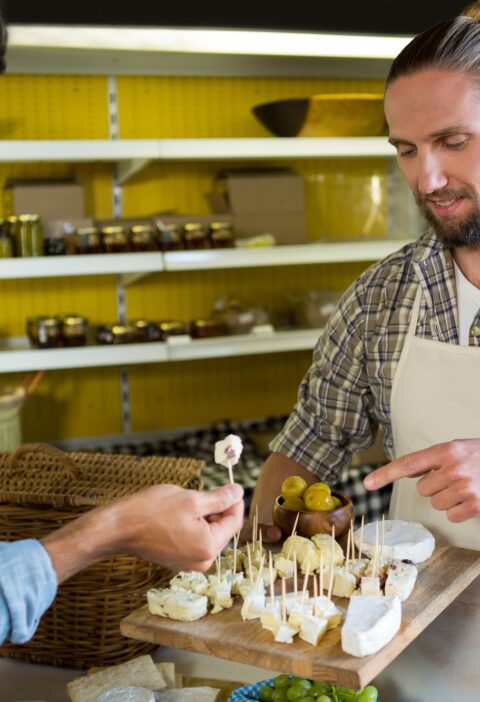 Staff showing a sample of cheese to customer at counter