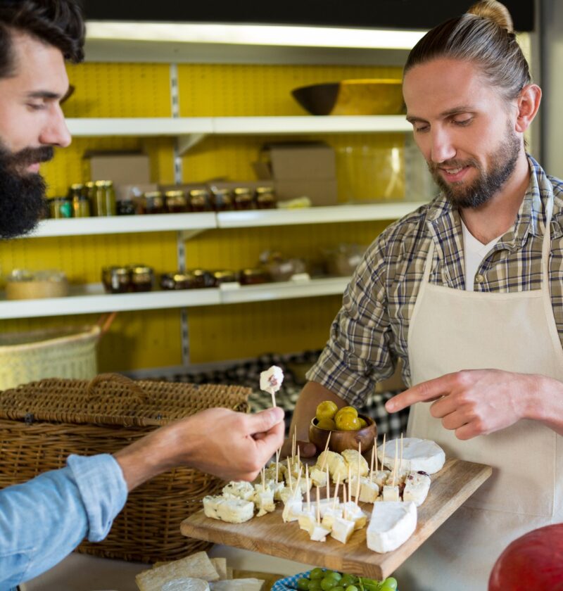 Staff showing a sample of cheese to customer at counter