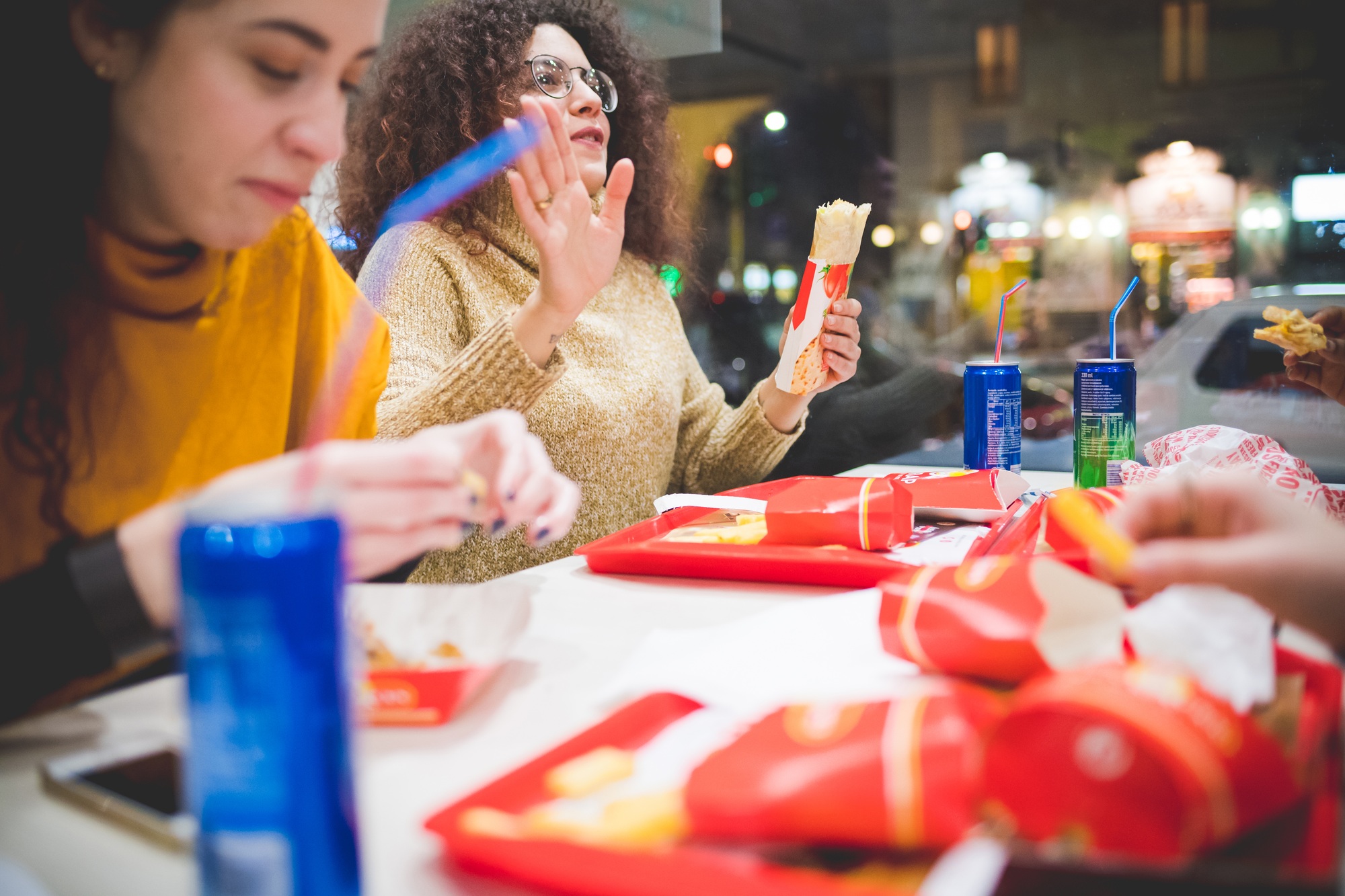 young curly woman eating in fast food with friends