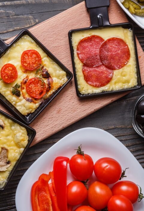 young woman is preparing a traditional Swiss cheese raclette