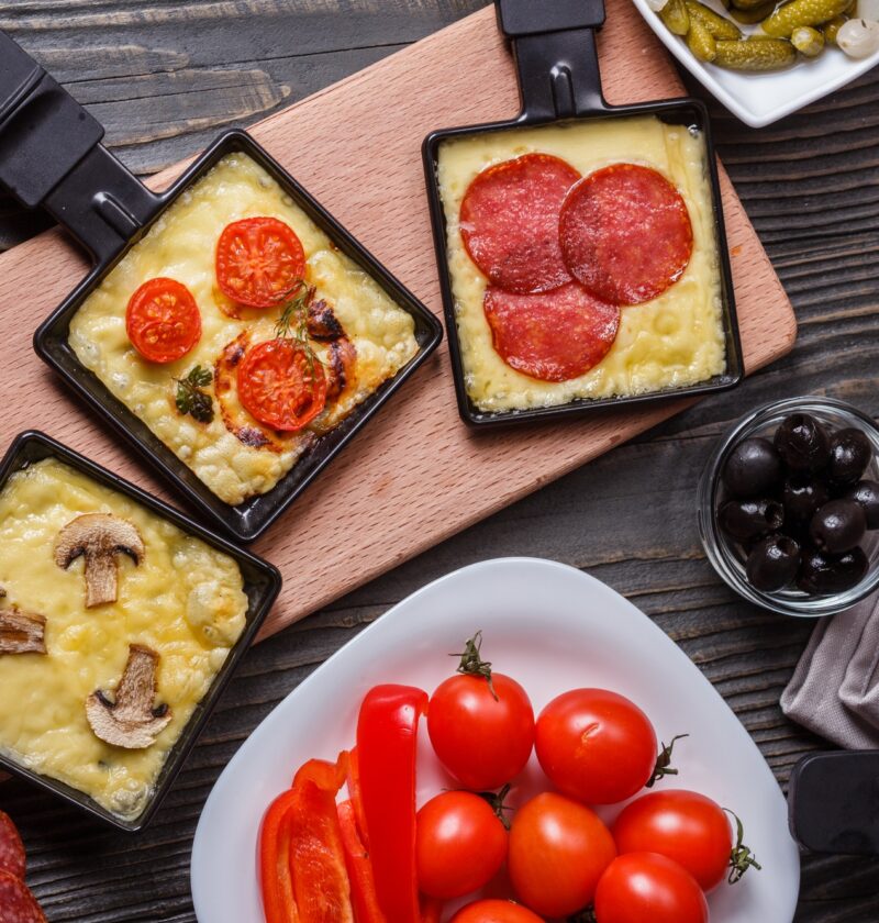 young woman is preparing a traditional Swiss cheese raclette