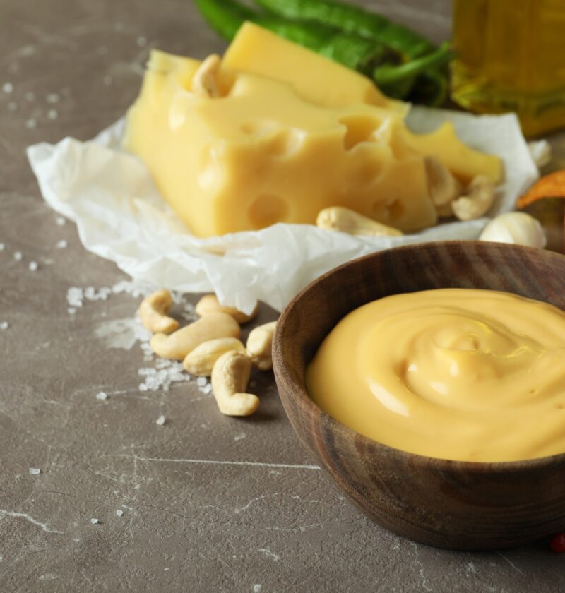 Bowls with cheese sauce and ingredients on gray textured table