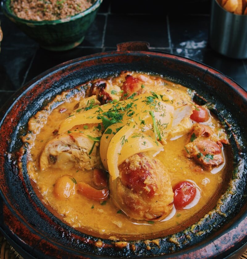 a bowl of food on a table next to a basket of fries