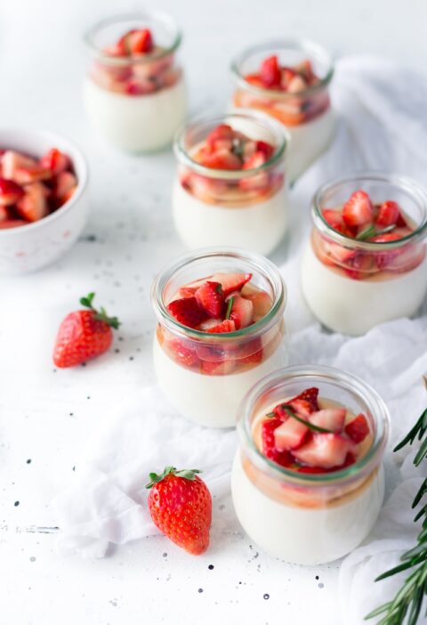 sliced strawberries in clear glass jar with cream