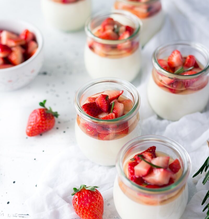sliced strawberries in clear glass jar with cream